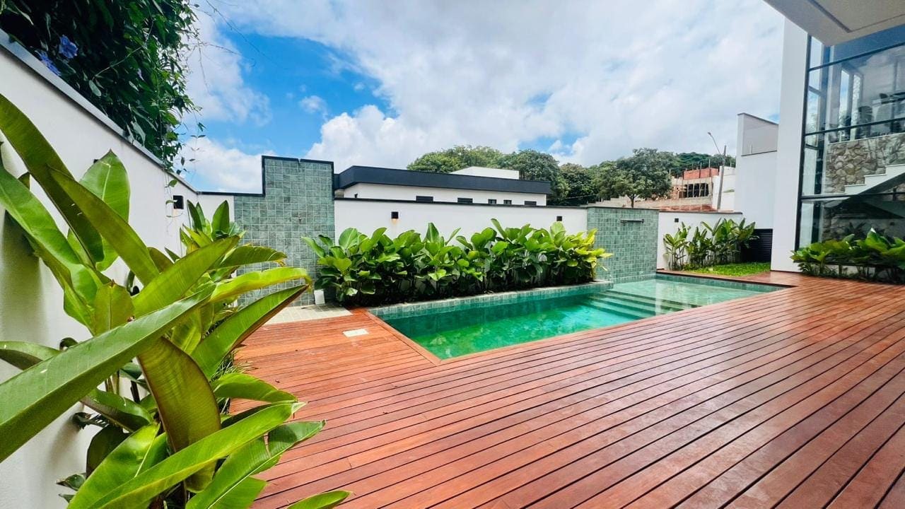 Piscina com deck de madeira e jardim em uma casa do Bosques do Junqueira